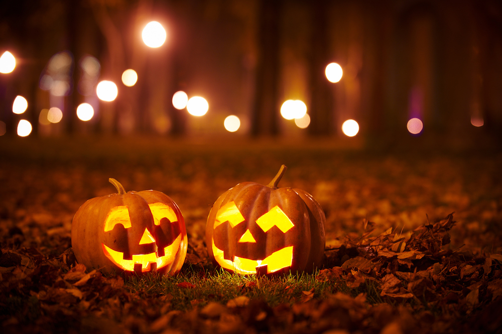 jack o lanterns on leaf covered ground at night